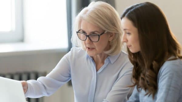 Mentoring, (c) Canva, fizkes, Getty Images Eine erfahrene und eine junge Frau gemeinsam vorm Laptop