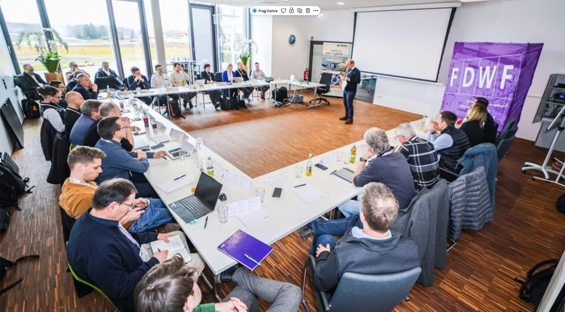 Etwa 30 Personen an Tischen in U-Form