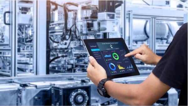Mann mnitr Tablet in der Hand vor einer Industriemaschine