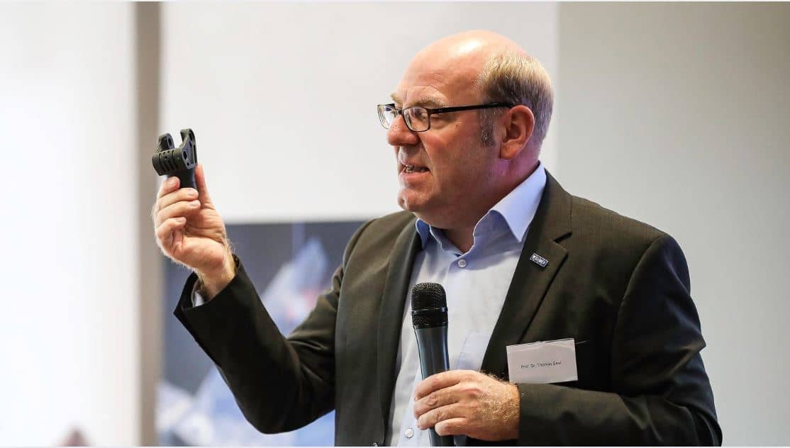 Prof. Thomas Seul hält ein schwarzes Bauteil in der rechten Hand