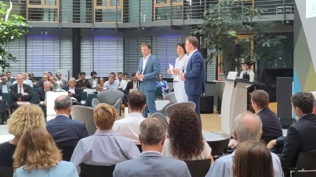 MdB Holger Mann, Andrea Frank, MdB Florian Müller auf der Bühne im Allianz-Forum Berlin mit Publikum, © AIF