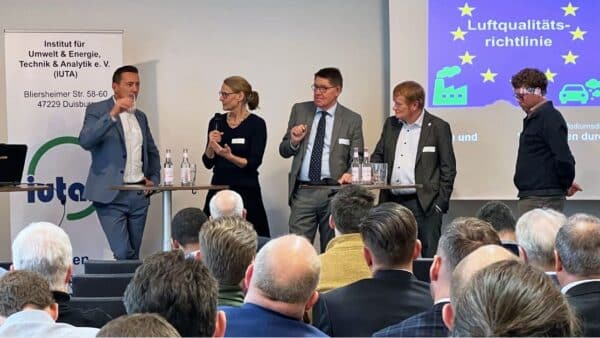 Diskussion mit fünf Experinnen und Experten an Stehtischen, vorn Hinterköpfe des Publikums, © IUTA