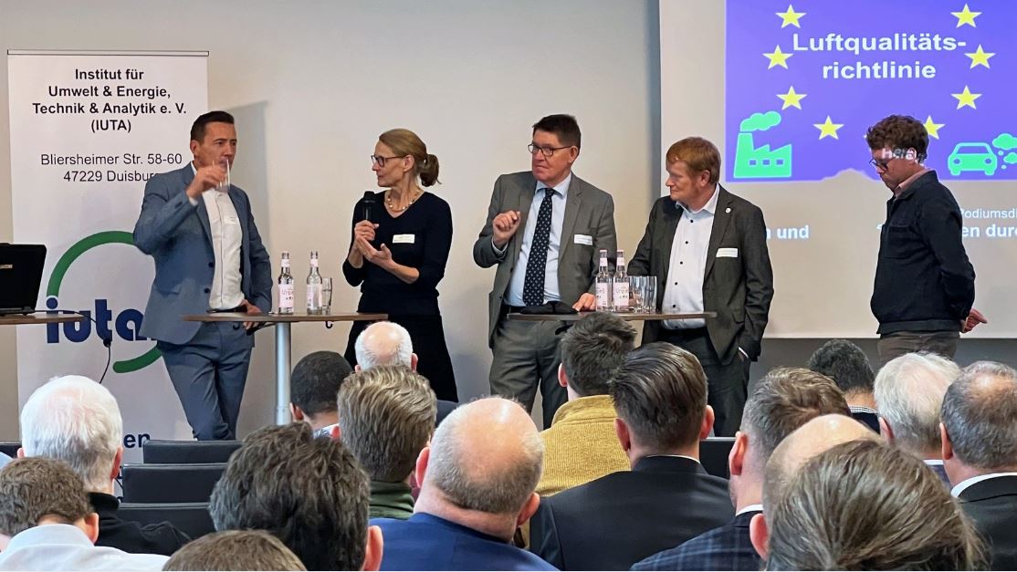 Diskussion mit fünf Experinnen und Experten an Stehtischen, vorn Hinterköpfe des Publikums, © IUTA